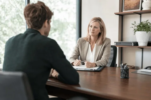 A person speaking with an HR manager across a desk in a calm, private office